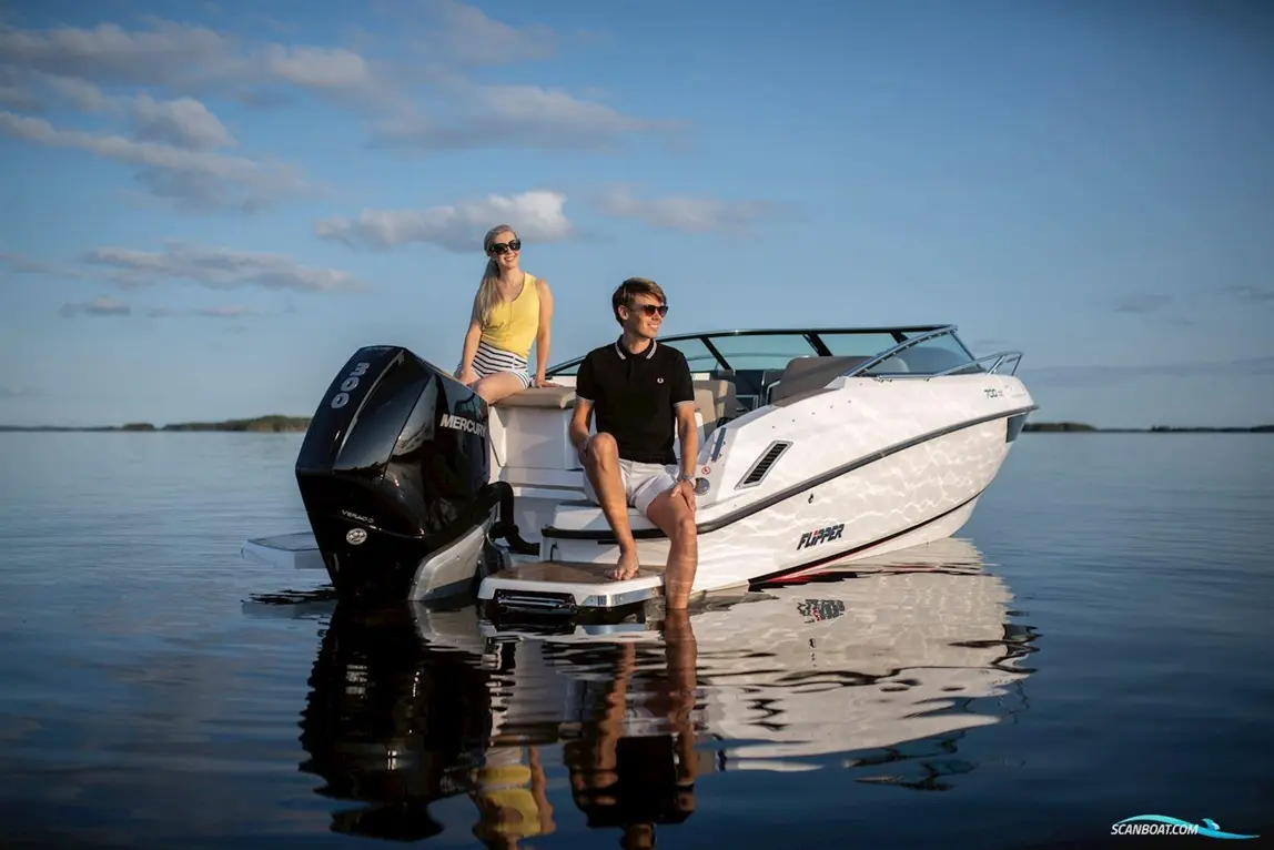 A man and woman relax on a Flipper boat, with a Mercury 300 outboard engine, in calm water under a blue sky.